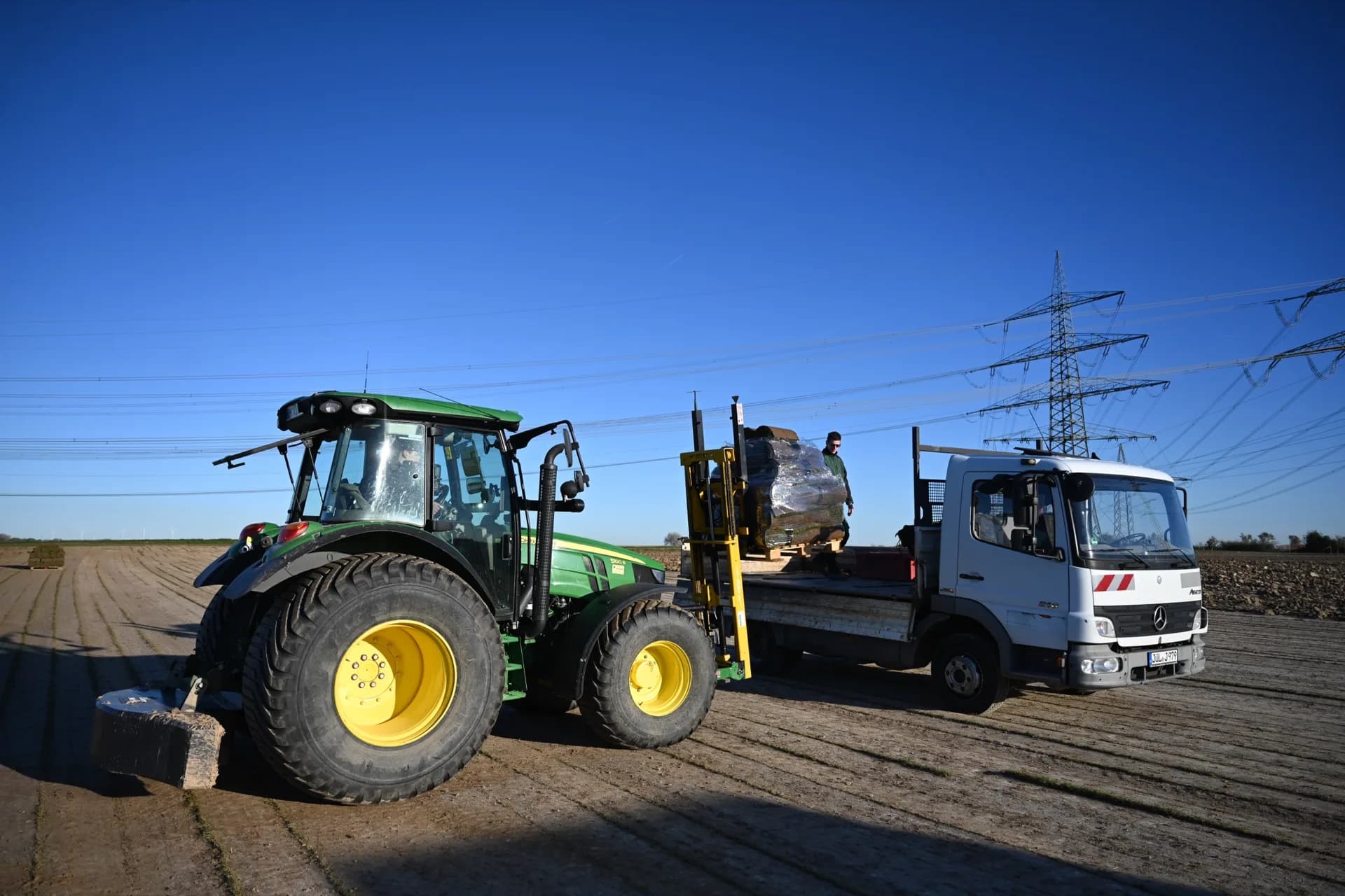 Traktor verlädt Rollrasen-Paletten auf den LKW