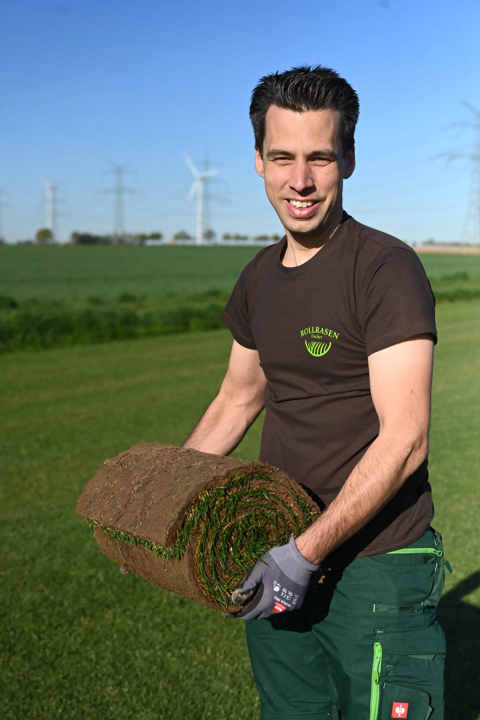Thomas Decker mit einer frisch geschälten Rolle Rollrasen auf dem Feld